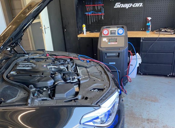 De aircomachine van Idema Autoservice naast een auto met open motorkap