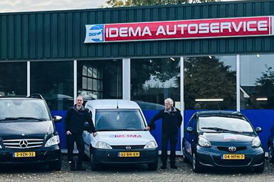 Twee mannen voor de gevel van Idema Autoservice, tussen een bestelbus en twee personenauto's