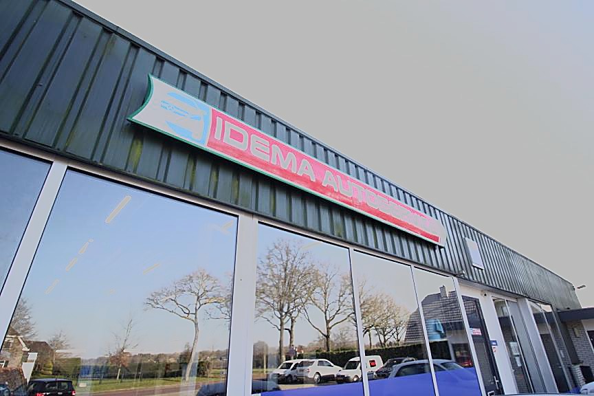 Het gevelbord van Idema Autoservice boven de glazen pui van de werkplaats