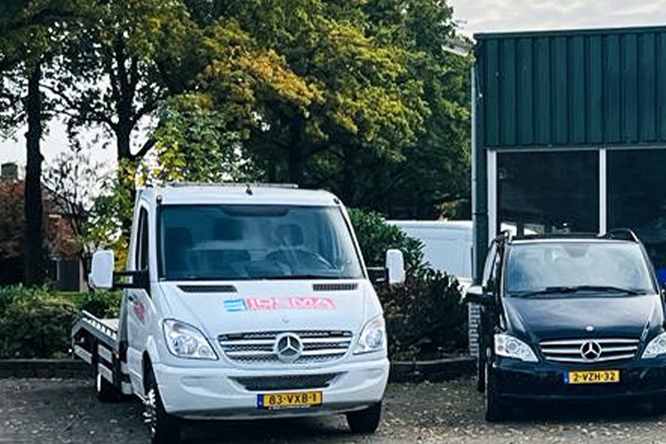 De lierwagen van Idema Autoservice naast het pand, met een zwarte bestelbus ernaast