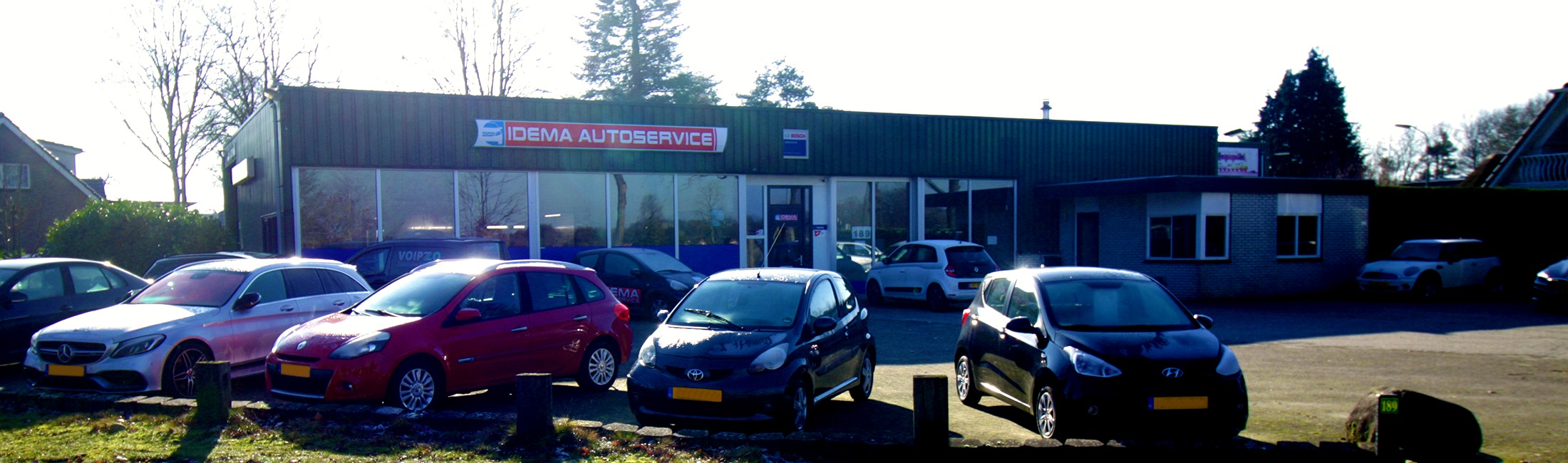 Het pand van Idema Autoservice aan de Sint Gerardusstraat in Emmen, gezien van de straat, met auto's op het terrein